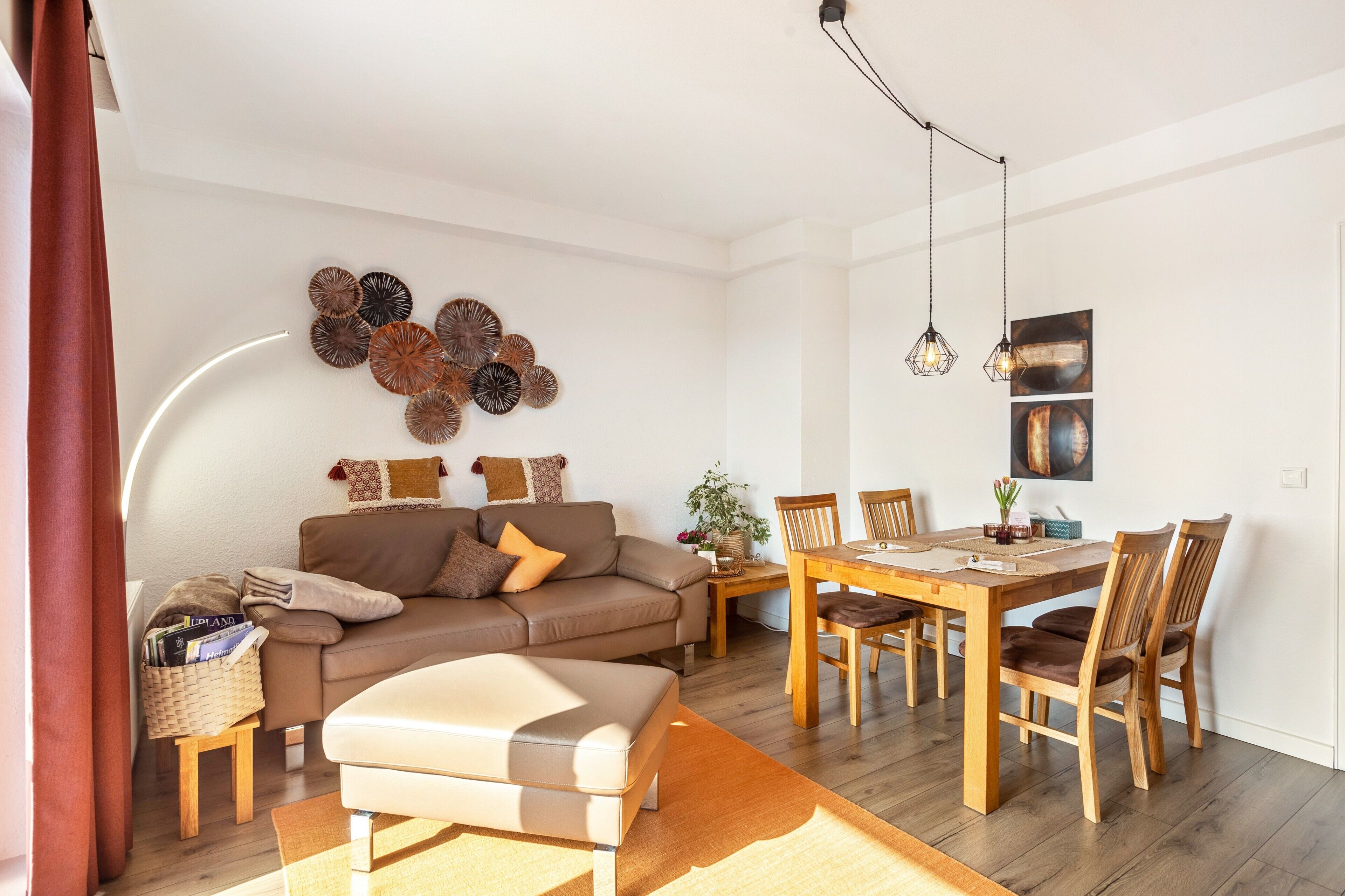 A living room with a sofa, ottoman, dining table, chairs, and wall decor.