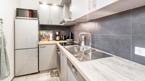 Cocina compacta equipada con refrigerador, microondas, estufa, fregadero y lavavajillas.