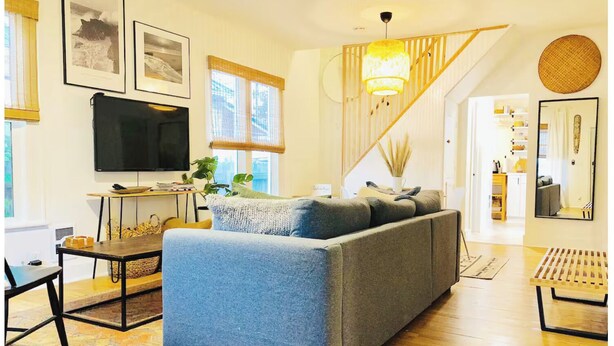 A living room with a sofa, a TV, a staircase, and a dining area. - Hip & Historic downtown Vancouver bungalow (Vancouver)