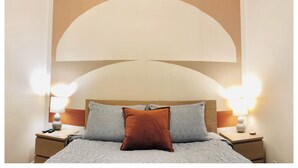 A bedroom with a bed, two bedside tables, and two wall-mounted lamps. - Hip & Historic downtown Vancouver bungalow (Vancouver)