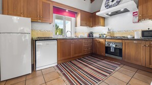 Eine Küche mit Holzausstattung, einem weißen Kühlschrank, einer Spülmaschine, einem Herd und einer Mikrowelle.