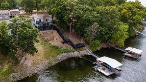 Une maison avec une jetée qui s’avance dans une rivière, entourée d’arbres.