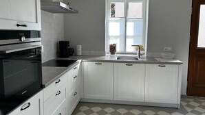 A modern kitchen with a built-in oven, a coffee maker, and a window with blinds.
