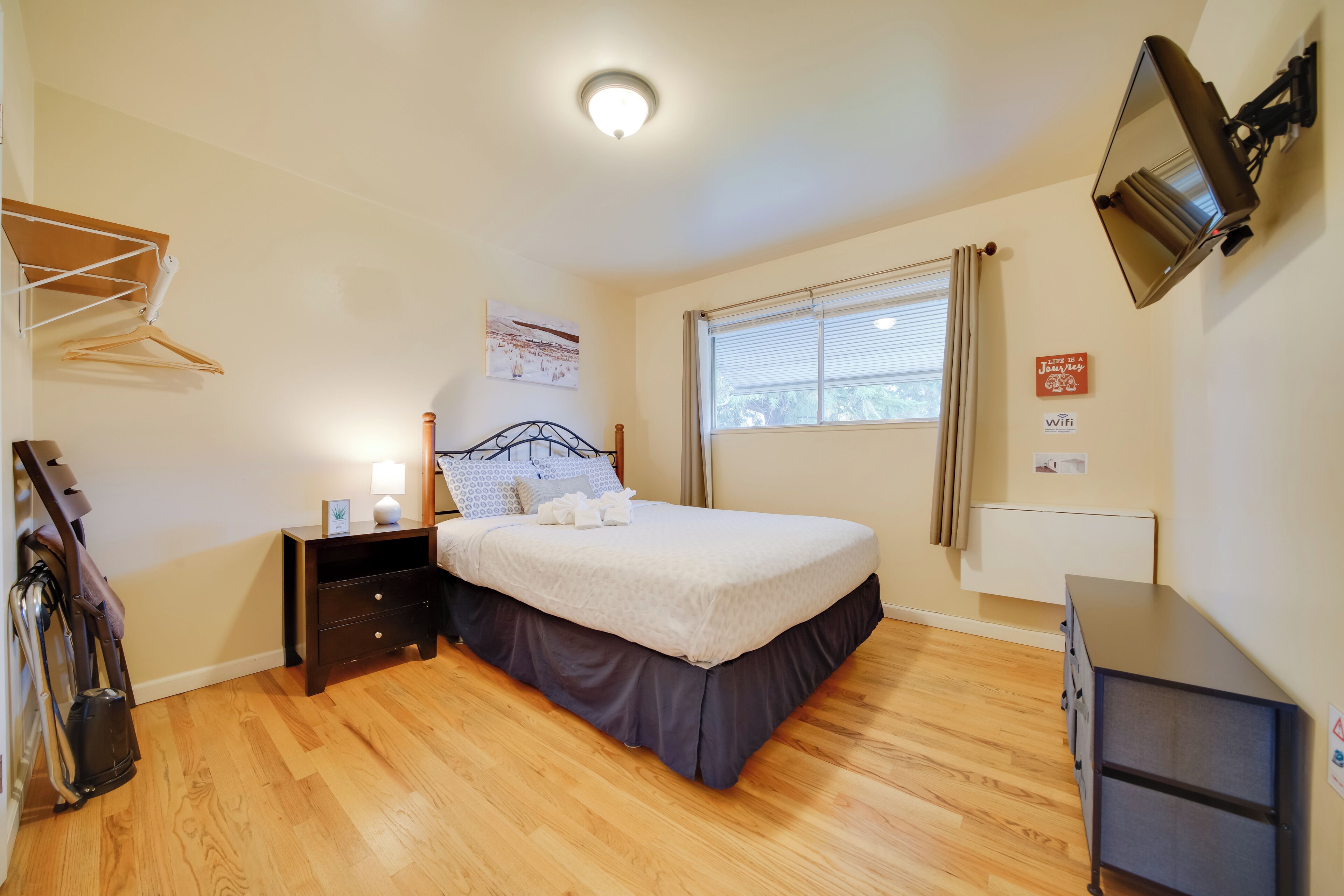 A neatly arranged bedroom with a bed, bedside table, and a wall-mounted TV.