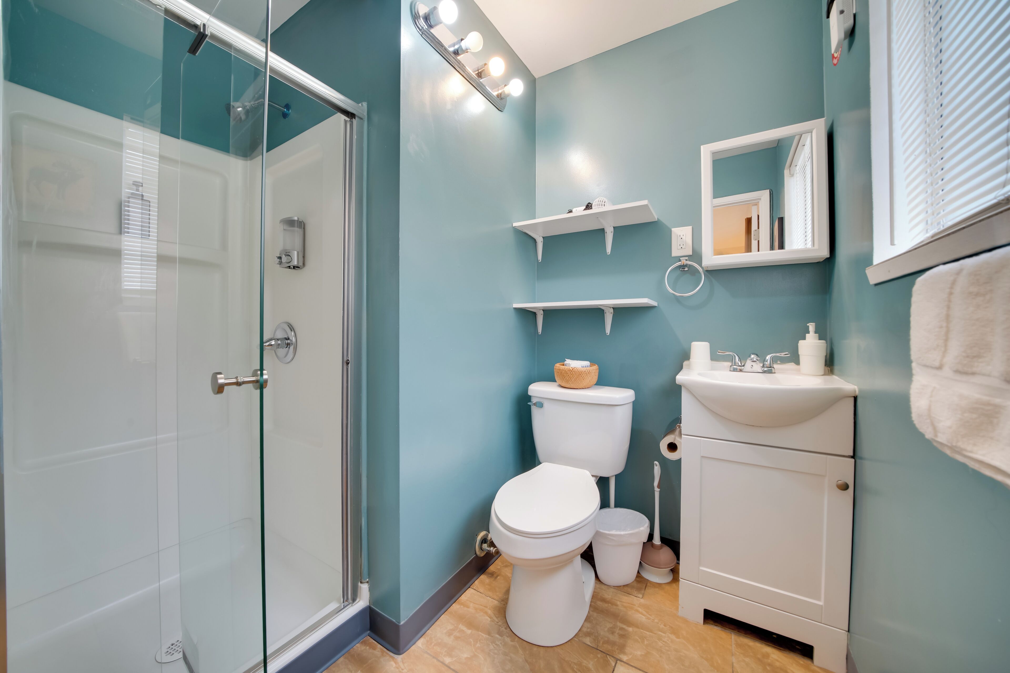 Une salle de bain avec une douche à parois de verre, des toilettes, un lavabo et un miroir.