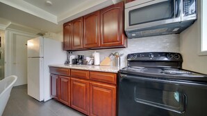 Une cuisine avec des meubles de rangement en bois, un réfrigérateur en acier inoxydable, une cuisinière noire et un four à micro-ondes.