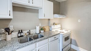 A kitchen with white cabinets, a granite countertop, a stainless steel sink, and a white stove. - 3 Mi to Dtwn: Omaha Escape w/ Game Room & Patio! (Omaha)