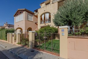 A residential building with a gated entrance, a balcony with curtains, and a well-maintained lawn. - GuestHost - Cozy 50 square meters villa, perfect for four people, with direct access from the garden.The property is just a 12-minute drive from Porto Giunco ​​beach and a 15-minute drive from Capo Carbonara beach.The accommodation comprises a living (Villasimius)
