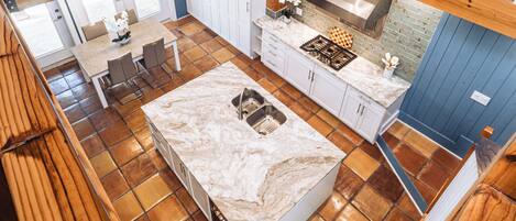 A spacious kitchen with a large island, white cabinets, and a stainless steel range hood.
