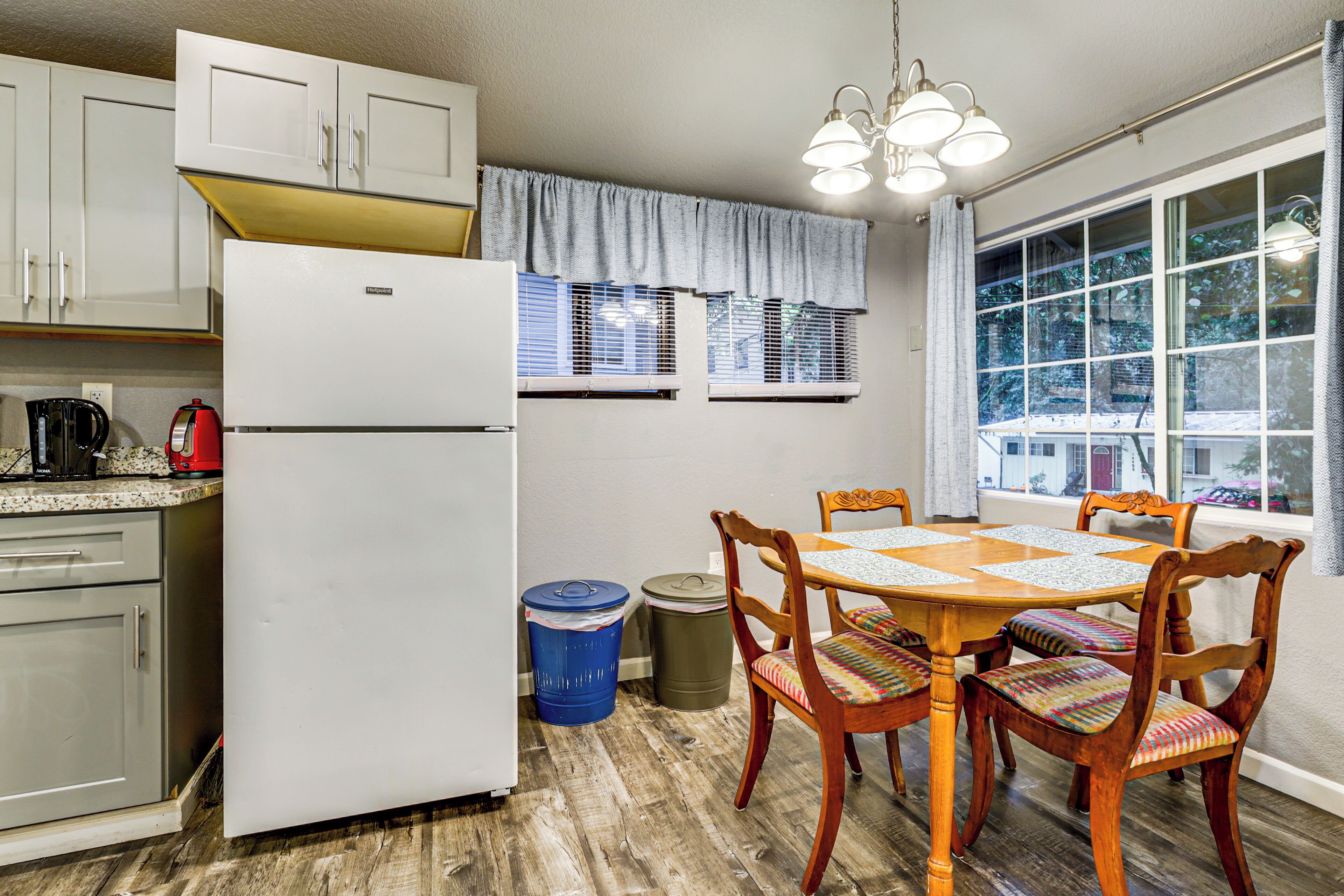 A kitchen with a refrigerator, stove, and dining table with chairs.
