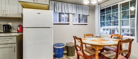 A kitchen with a refrigerator, stove, and dining table with chairs.
