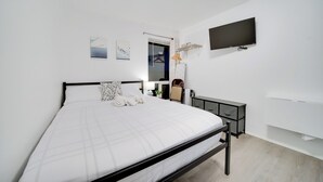 Un dormitorio moderno con cama, televisor, armario y mesita de noche.