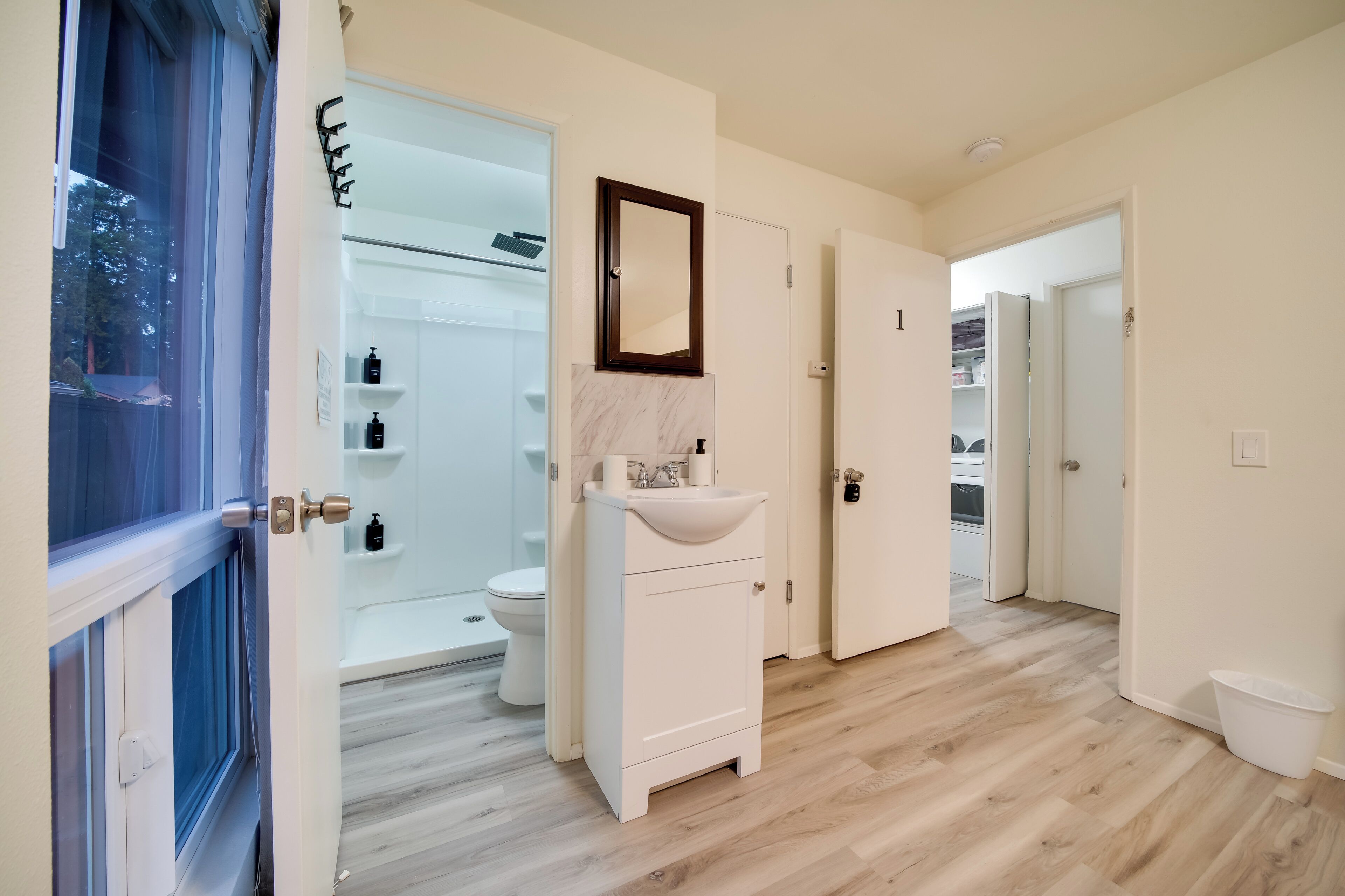 A modern bathroom with a white sink, a mirror, and a shower area.