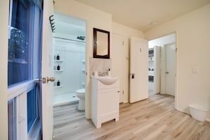 A modern bathroom with a white sink, a mirror, and a shower area.