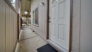 A covered porch with a white door, a window, and a small outdoor seating area. - Eastside Tech Hub Home Base Near I-90 & Factoria! (Bellevue)