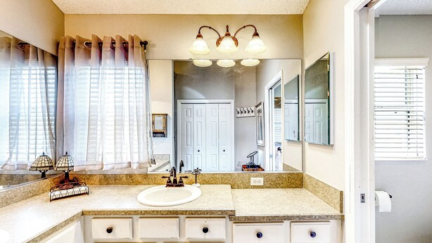 A bathroom with a double sink, vanity with drawers, a mirror, and a ceiling light fixture. - All-season 3BR w/ Large Outdoor Area (The Villages)