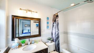 A bathroom with a large mirror, a sink, a toilet, and a shower.