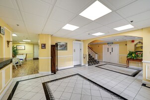 Un hall de hotel con suelo de baldosas, una escalera y una zona de recepción.