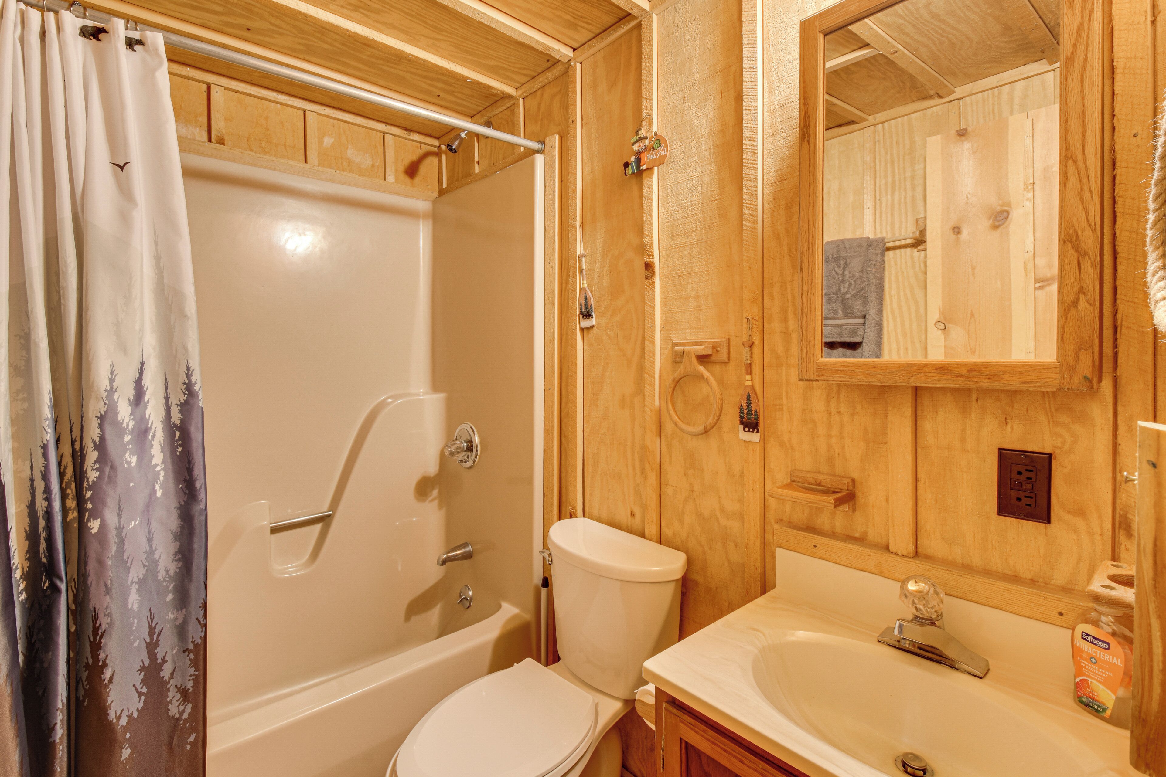 Un baño de madera con bañera, inodoro y lavamanos.