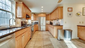 Cucina con mobili in legno, elettrodomestici in acciaio inossidabile e pavimento piastrellato.