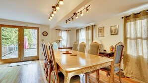Una sala da pranzo con tavolo e sedie in legno, ampie finestre e vista sull'esterno.