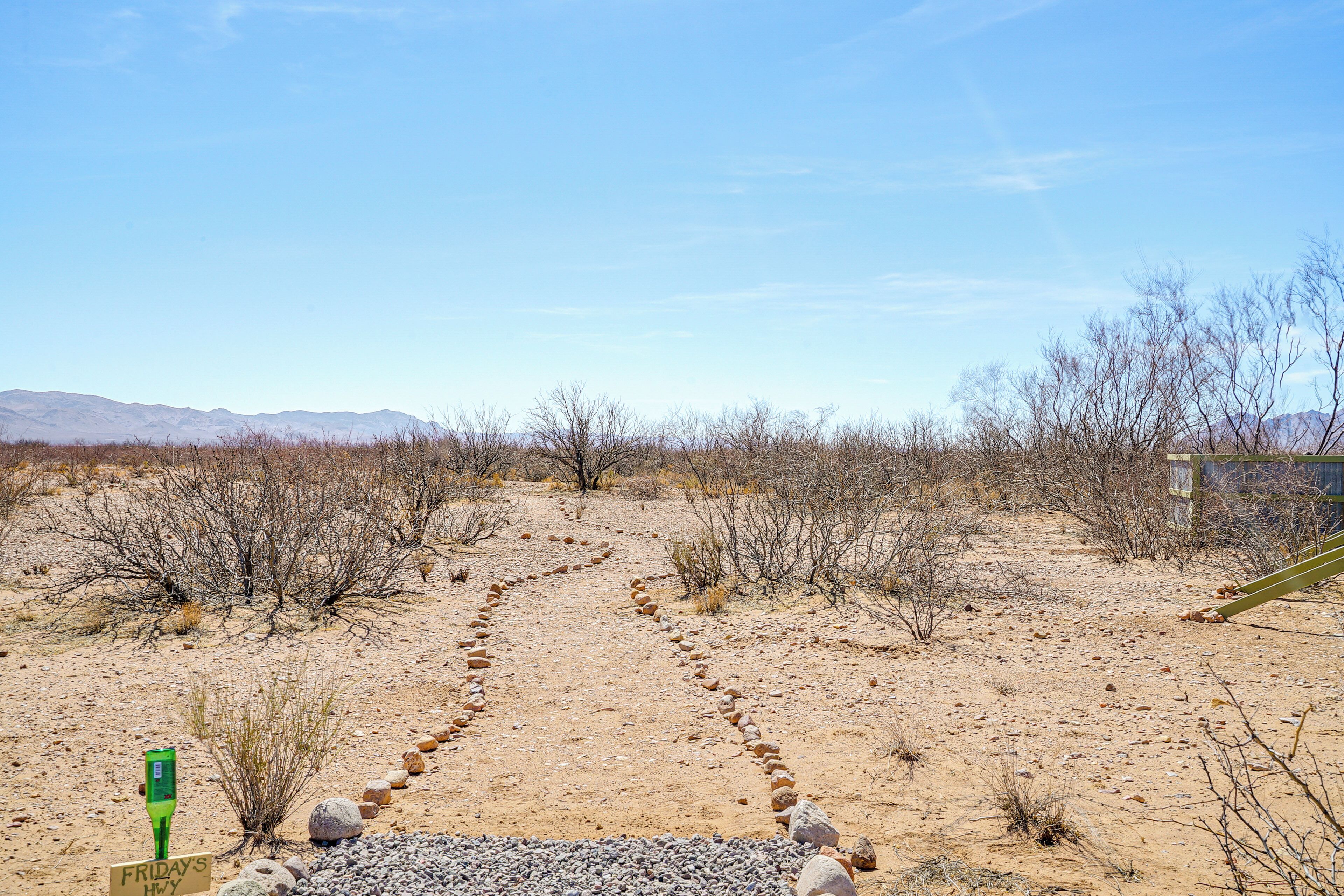 A desert landscape with a dirt path leading to a building.