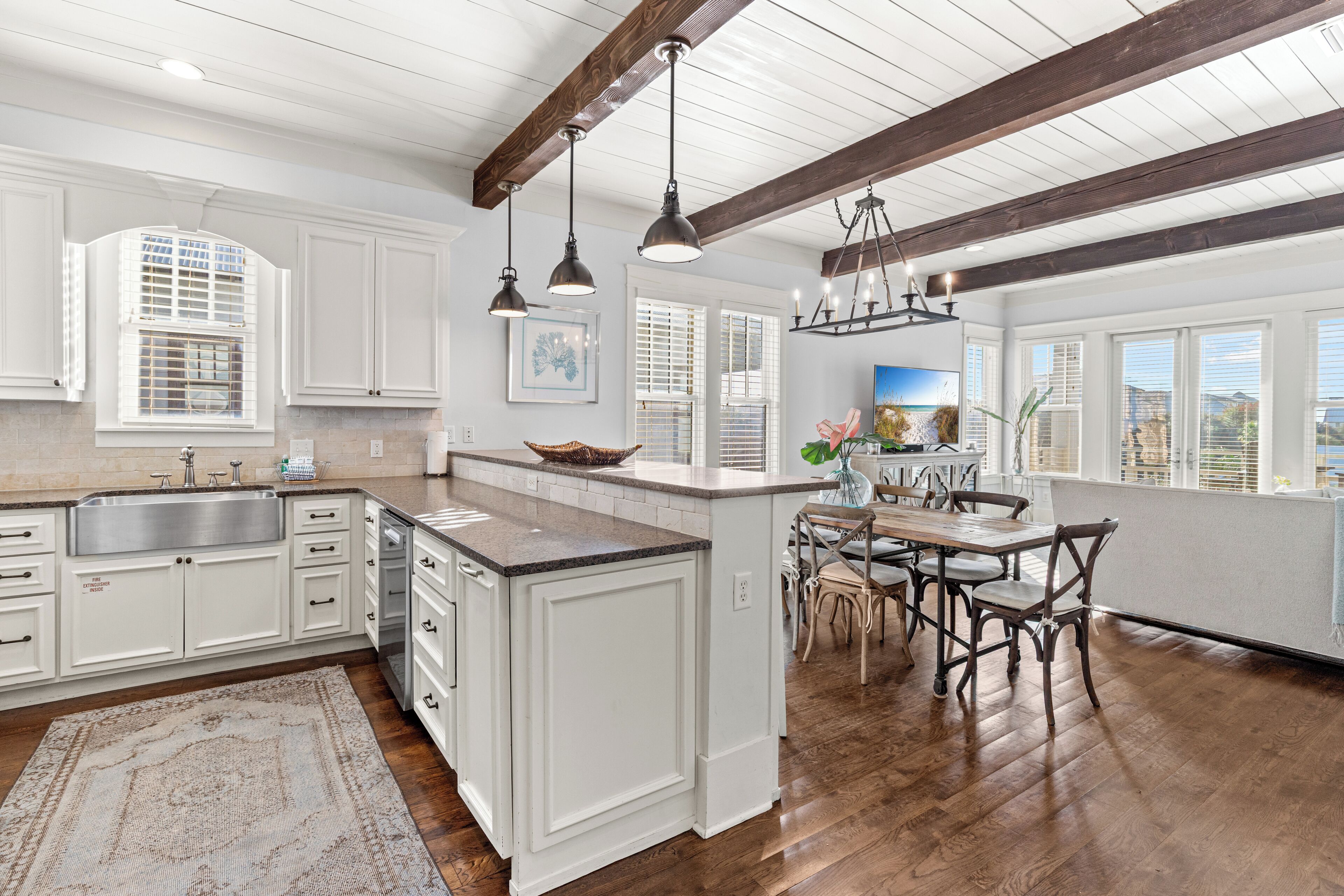 A spacious kitchen with white cabinetry, a large island, and a dining area with wooden chairs.