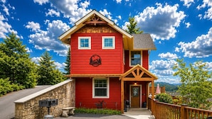 Un edificio rojo de dos pisos con un muro de piedra, un buzón y una terraza de madera.