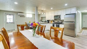 A modern kitchen with white cabinets, stainless steel appliances, and a dining area with a wooden table and chairs. - 3 Acres of Serenity! Countryside Home in Dickinson (Dickinson)