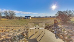 Two white chairs facing each other on a concrete path with a stone wall on one side and a grassy field with a building in the distance. - 3 Acres of Serenity! Countryside Home in Dickinson (Dickinson)