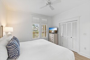 A bedroom with a bed, a television, a dresser, and a window with shutters. - Idle Hour in WaterColor | 2bd + Loft, 2 bikes, Steps to WaterColor Beach Club (Santa Rosa Beach)