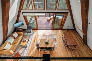 Ein Loft-Zimmer mit Holzboden, einer Couch, einem Couchtisch und Blick auf eine Terrasse sowie einen Außenbereich.