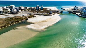 Une vue aérienne d’une zone côtière avec une plage, un pont et des bâtiments.