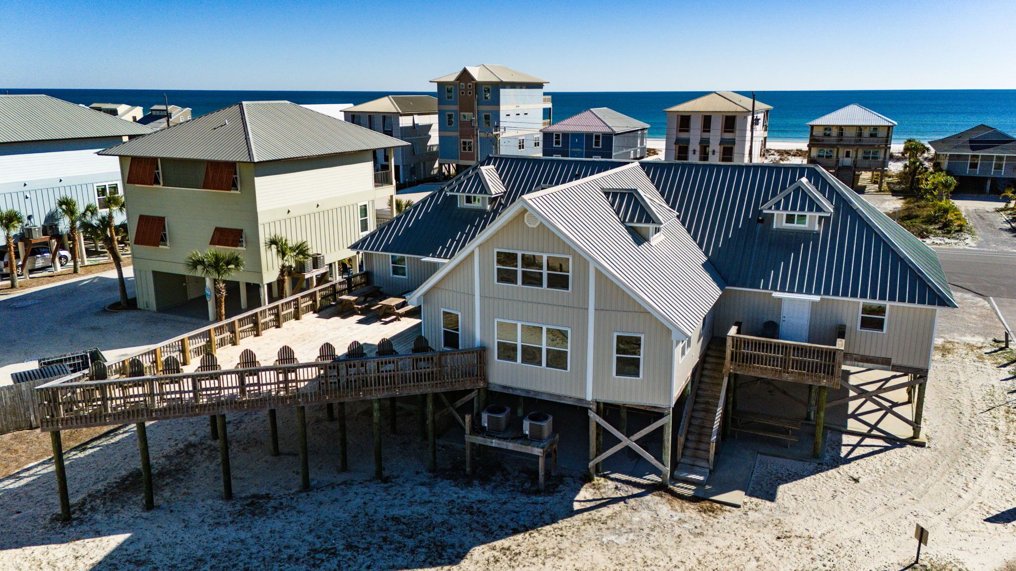 Una proprietà fronte spiaggia con una casa principale dotata di un'ampia terrazza e un edificio separato con un balcone.