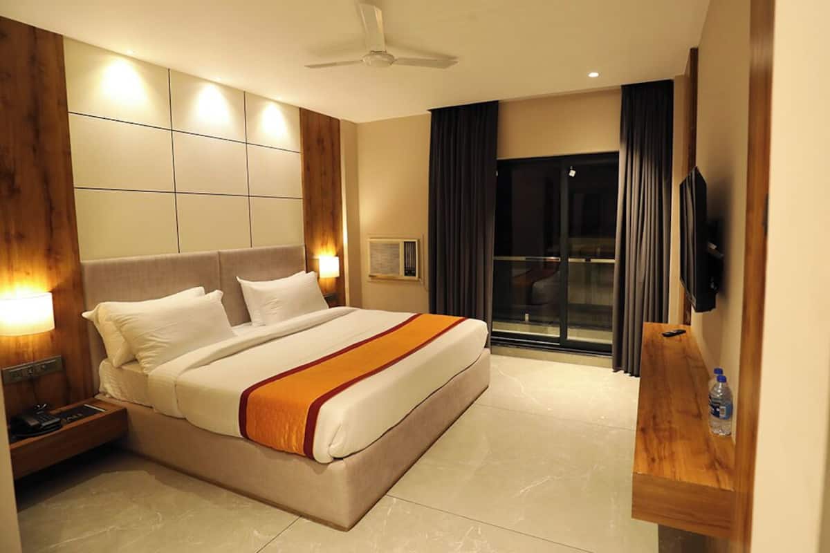 A modern hotel room with a large bed, a ceiling fan, a TV, and a sliding glass door to the outside.