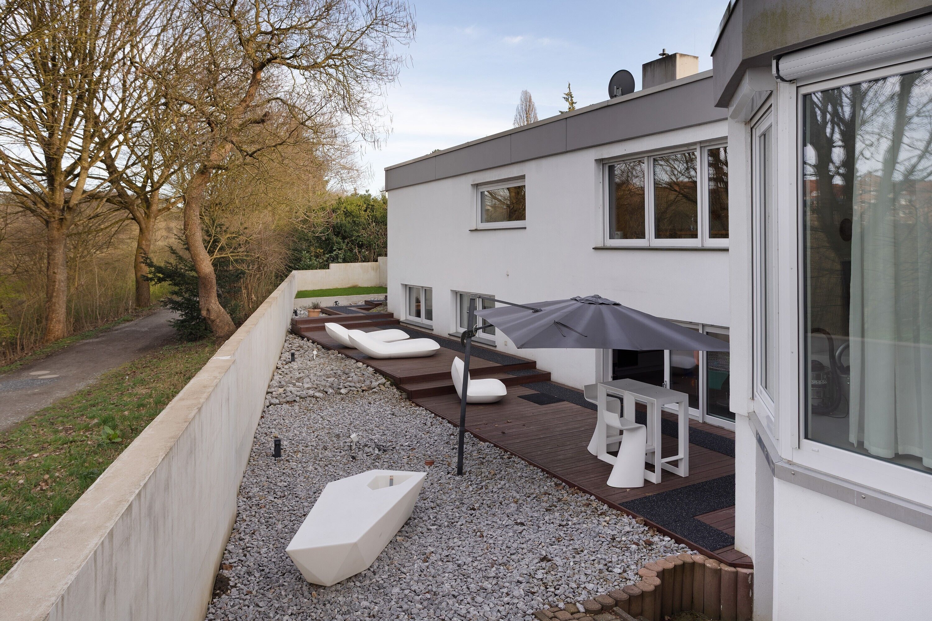 A modern house with a patio area featuring outdoor furniture and a large umbrella.