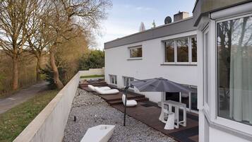 A modern house with a patio area featuring outdoor furniture and a large umbrella.