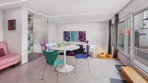 Un intérieur moderne avec une table ronde, des chaises, un canapé rose et des œuvres d’art accrochées aux murs.