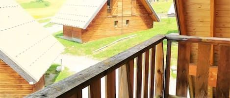 A wooden cabin with a balcony overlooking a rural landscape.