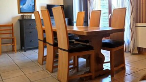 A dining area with a wooden table and chairs, a television, a refrigerator, and a hanging light fixture. - Chalet for 7 people - Les Flocons du Soleil (LE DEVOLUY)