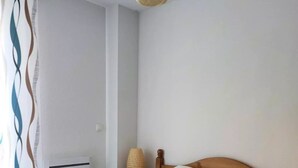 A neatly made bed with a red blanket and two pillows, a bedside lamp, and a window with a curtain. - Chalet for 7 people - Les Flocons du Soleil (LE DEVOLUY)