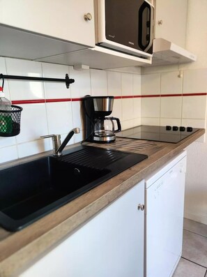 Une cuisine avec un évier noir, une machine à café et un four à micro-ondes.