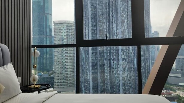 A hotel room with a large window offering a view of high-rise buildings. - Scarletz Suites klcc by Signature Apartment (Kuala Lumpur)