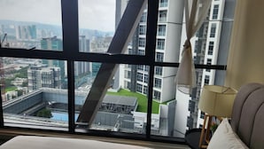 A hotel room with a large window offering a city view, a bed, a lamp, and a view of a bridge and buildings. - Scarletz Suites klcc by Signature Apartment (Kuala Lumpur)