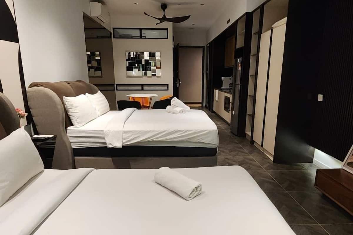Una habitación de hotel moderna con una cama grande, una mesita y una kitchenette.
