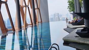 An infinity pool with a city view, modern architecture, and lounge seating. - Scarletz Suites klcc by Signature Apartment (Kuala Lumpur)