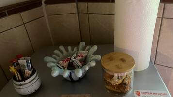 A table with a container of pens, a decorative bowl with chocolates, and a jar of cookies.