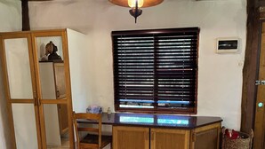 A room with a wooden cabinet, a chair, a window with blinds, and a small table. - Enchanting Forest Cottage in Hogsback, village of beautiful hikes and waterfalls (Hogsback)