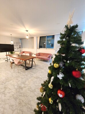 Una sala de estar con una mesa de comedor, dos sofás, un árbol de Navidad y un televisor.