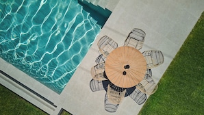Vista aérea de uma piscina com área de estar circular ao ar livre e um guarda-sol central.